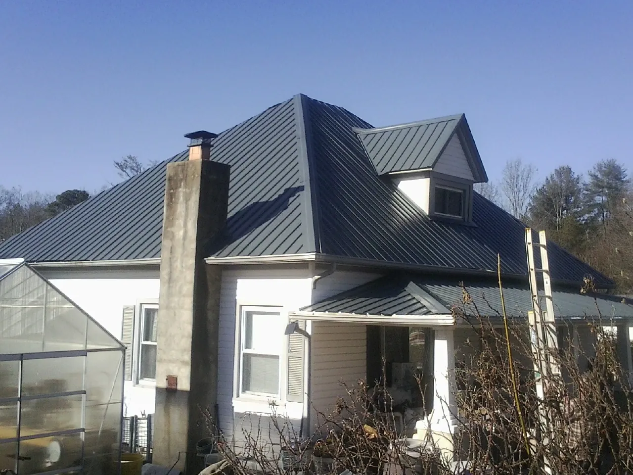 Dark blue standing seam metal roof on a white farmhouse with dormer — Slate & Tile Roof Repair by Roofing Brothers in Brimfield