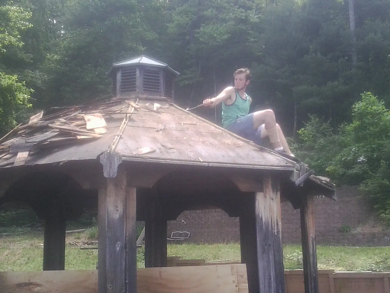 Tearing the old roof off a wooden gazebo before new shakes in Brimfield