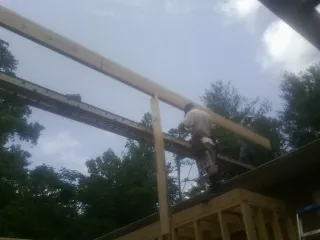 Carpenter setting a ridge beam over a new addition frame — Ice Dam Removal by Roofing Brothers in Brimfield