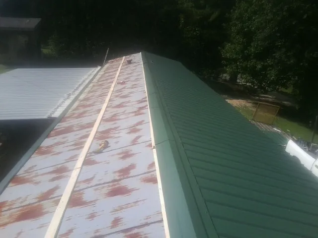 Old rusted panels beside newly installed green metal roofing — Wind Damage Roof Repair by Roofing Brothers in Brimfield