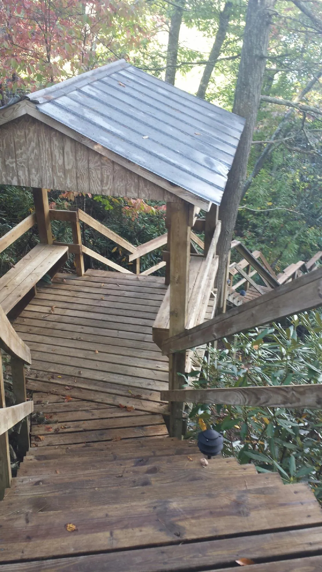 Metal roofed shelter over wooden steps on a wooded walkway — Skylight Repair & Installation work by our crew in Brimfield