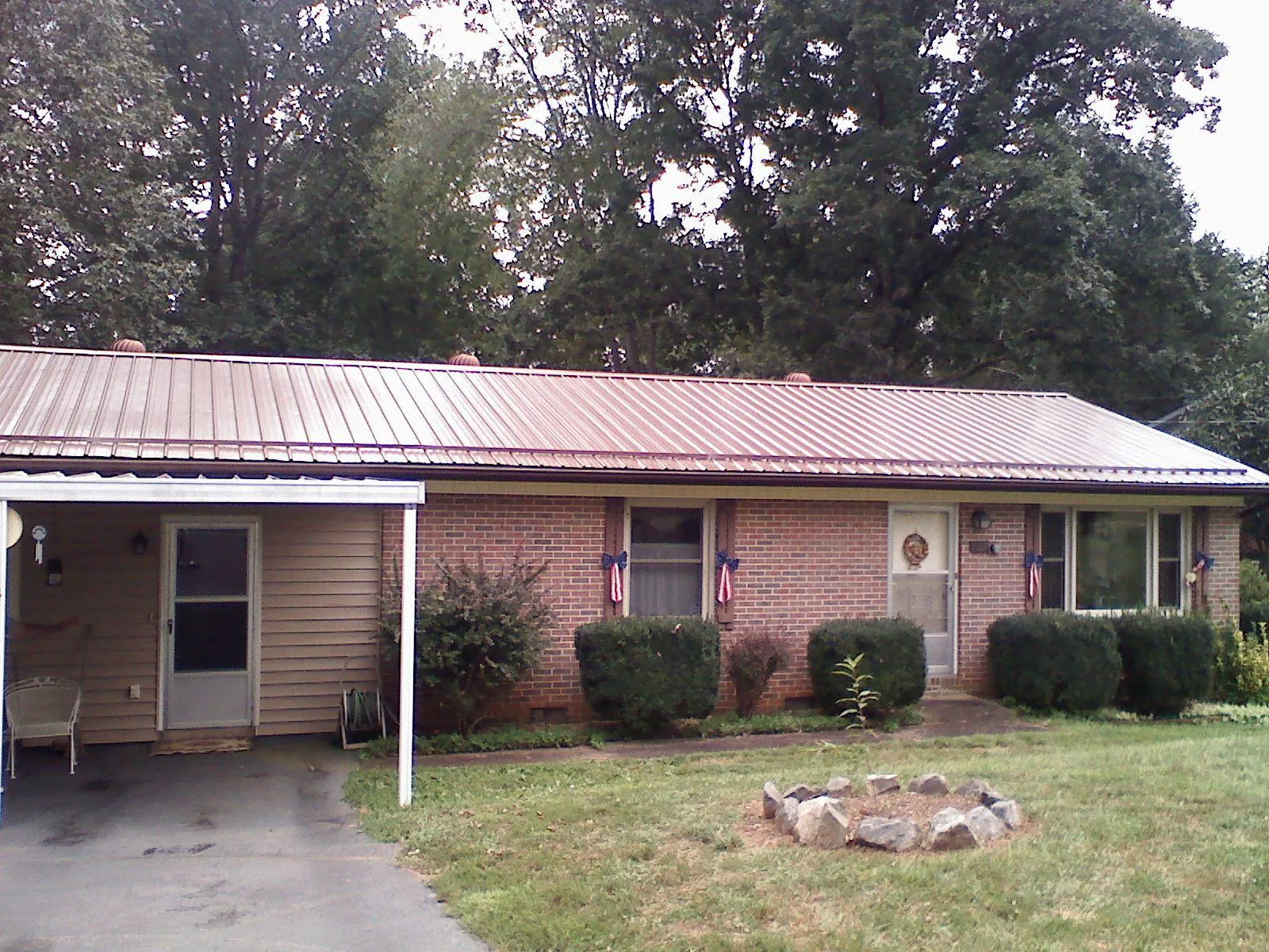 Bronze metal roof and carport on a brick ranch home — Roof Repair work by our crew in Brimfield
